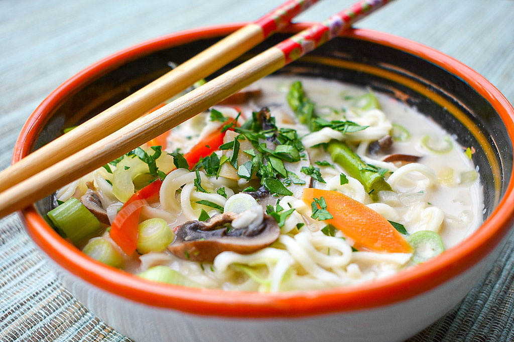 Thailändische Kokos-Champignonsuppe in Suppenschale mit Stäbchen